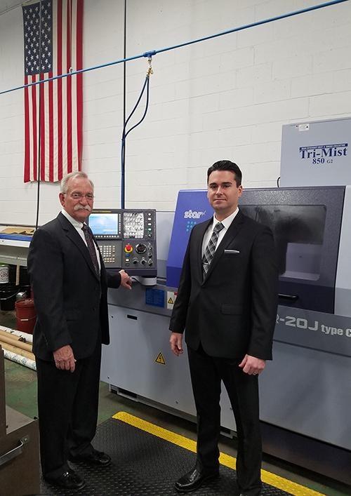 Doug Dolinar (L), Nick Tomes, (R) standing in front of a Star Swiss Screw machine.